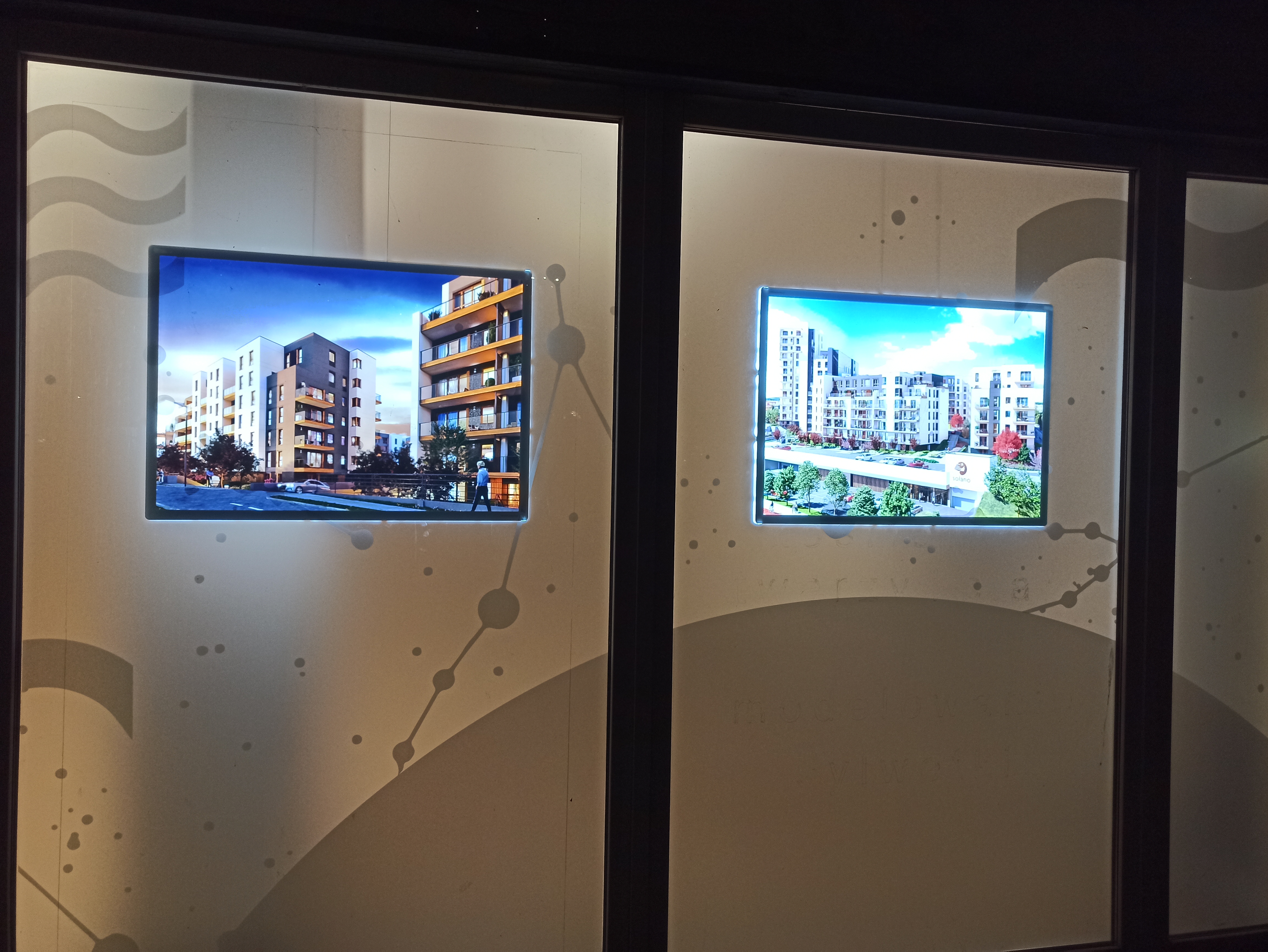 Witryna Budimex z dużymi ekranami LED prezentującymi wizualizacje inwestycji