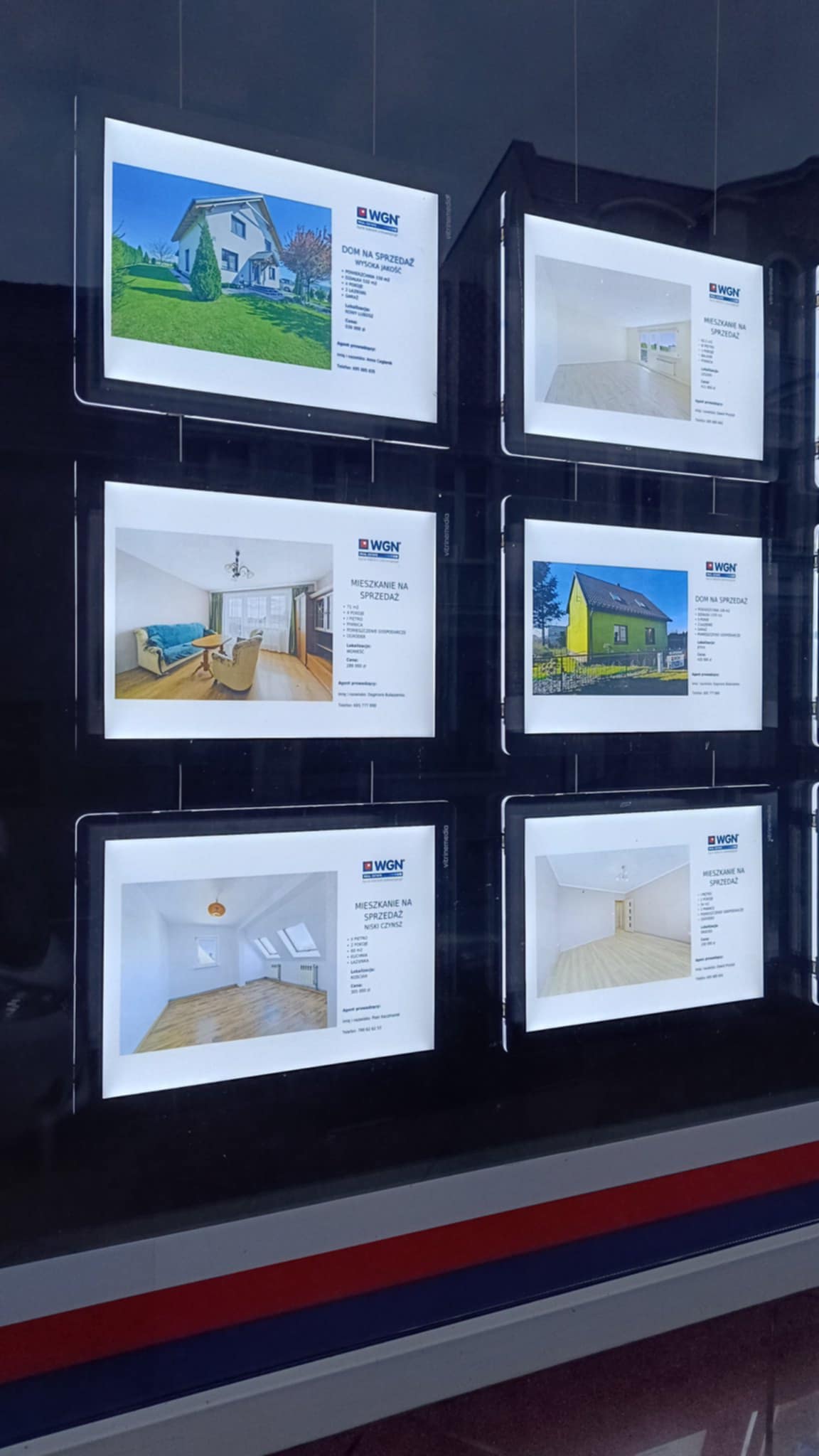 Witryna agencji nieruchomości z podświetlanymi ekspozytorami LED nocą