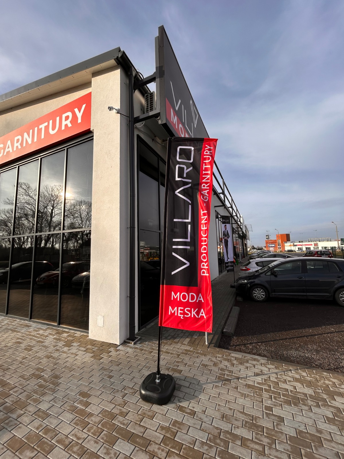 Flaga reklamowa przed lokalem handlowym jako przykład reklamy outdoorowej wykorzystywanej na zewnątrz