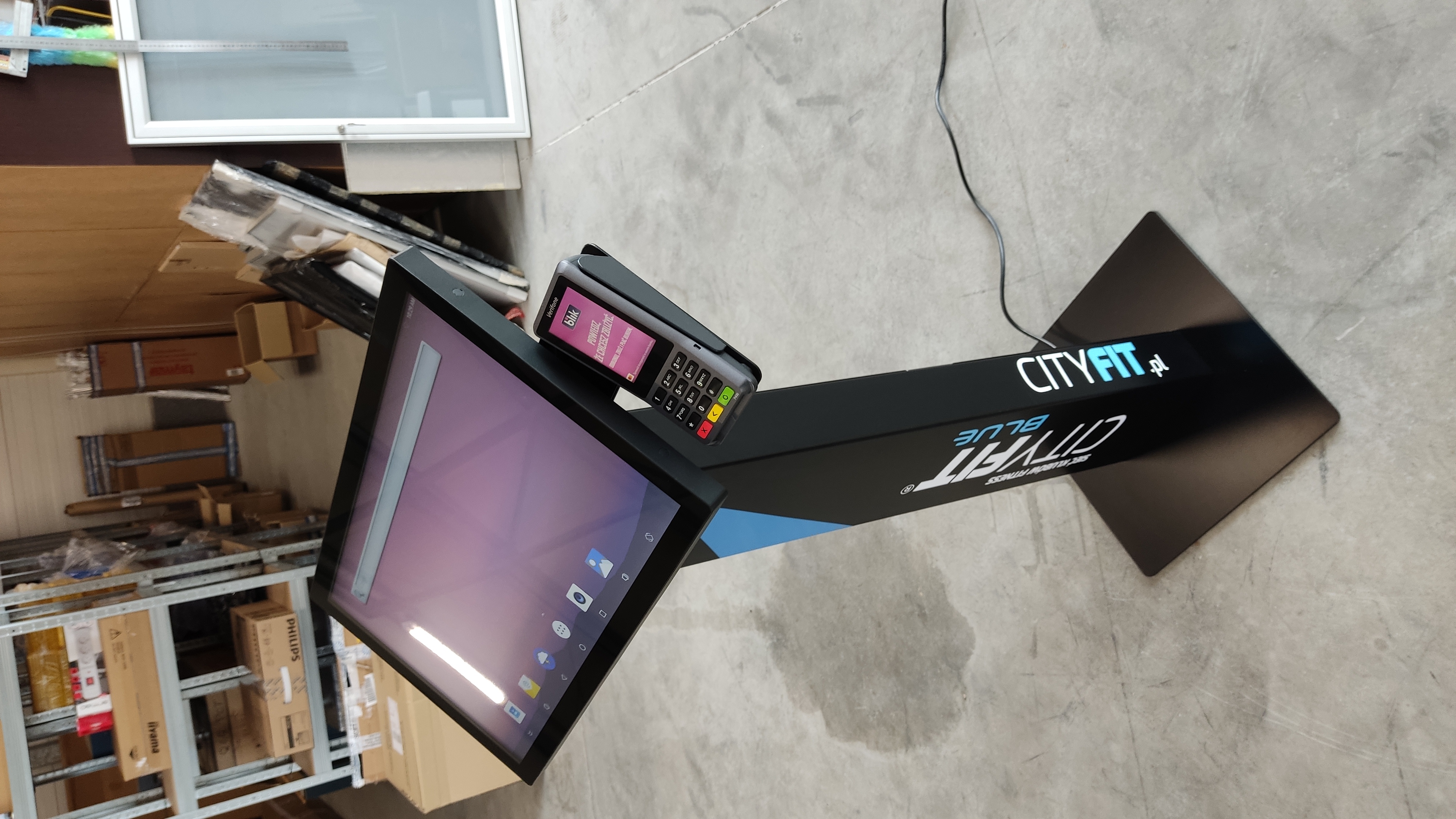 Nowoczesny infokiosk z ekranem dotykowym i terminalem płatniczym, oznaczony logotypem CITYFIT.