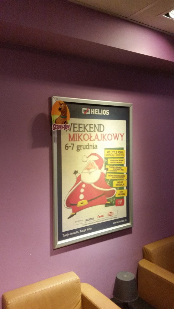 Reklamowy plakat świąteczny w aluminiowej ramie OWZ w holu kina Helios, zawieszony na fioletowej ścianie