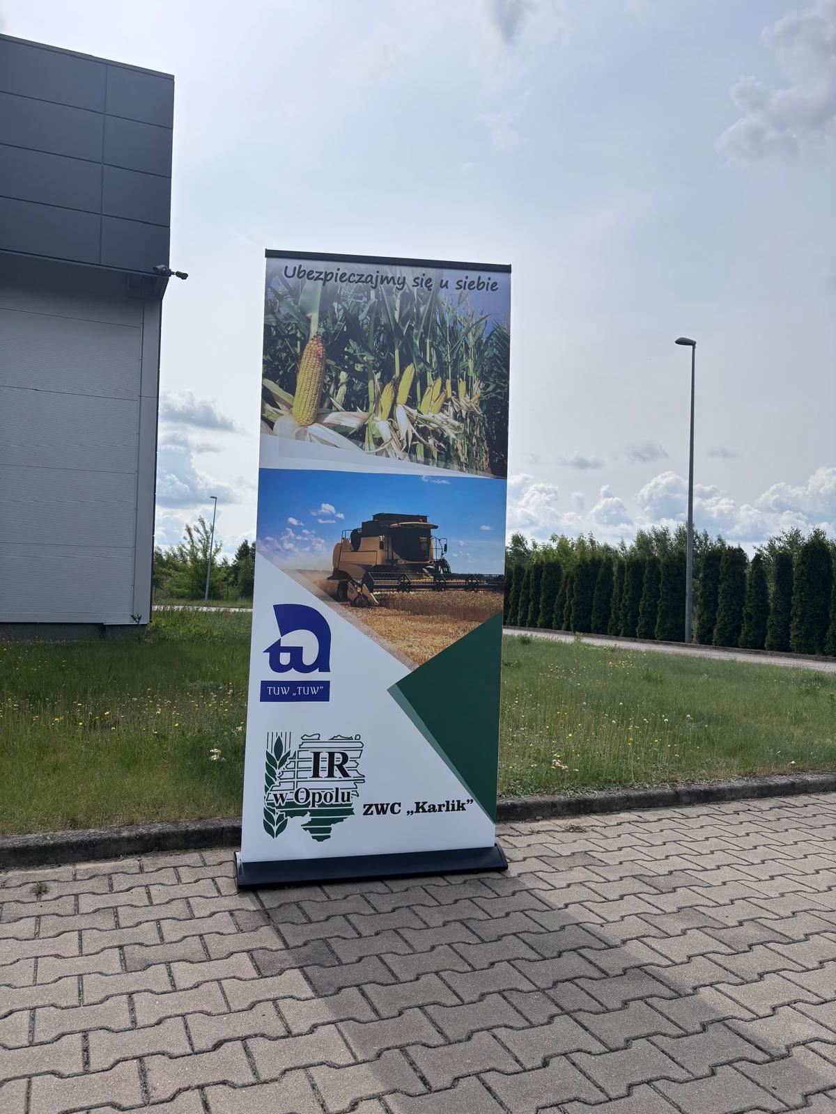 Roll-up reklamowy TUW prezentujący grafikę rolniczą, ustawiony na zewnątrz przed budynkiem.