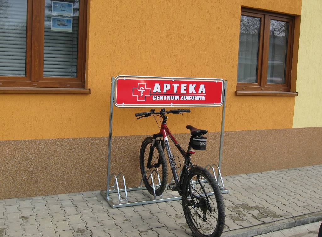 stojak rowerowy przed apteką z zaparkowanym rowerem