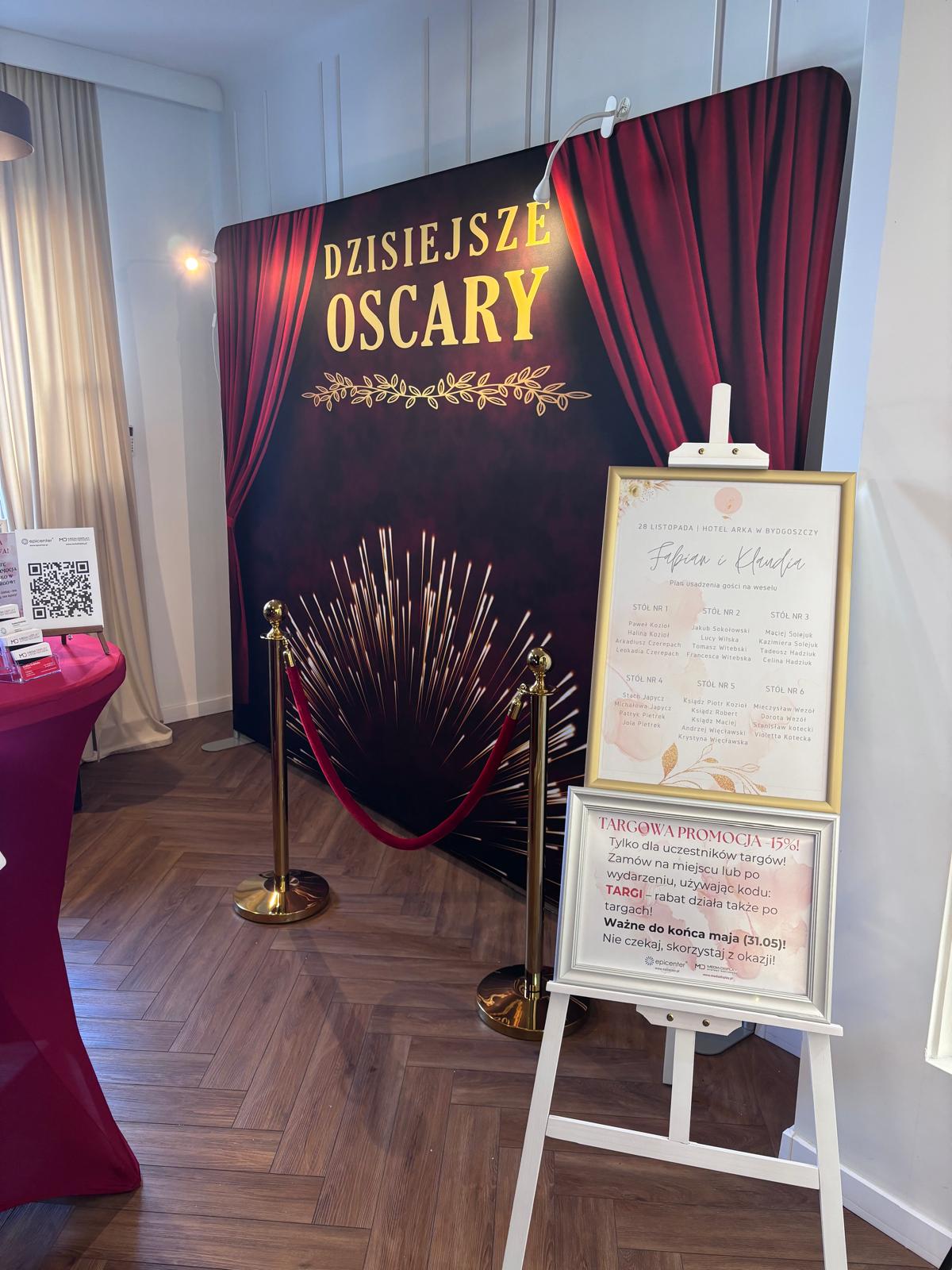 Ścianka reklamowa z motywem Oscarów oraz sztaluga z ramkami prezentującymi ofertę i promocję targową – elegancka aranżacja stoiska.